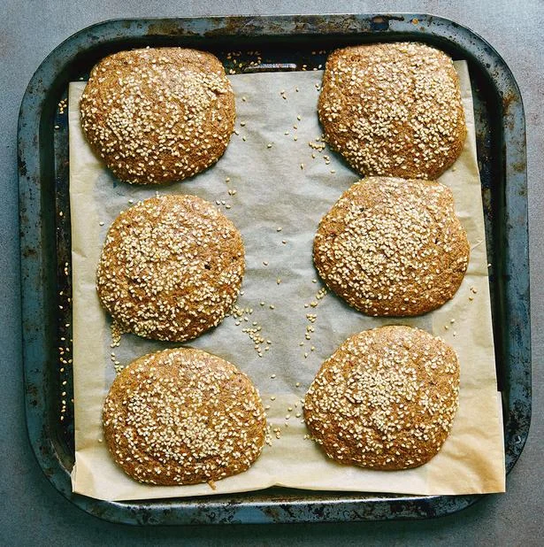 Six flaxseed buns on parchment paper in a baking tray