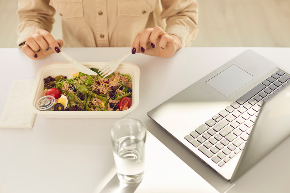 A woman enjoying a healthy salad at her workspace