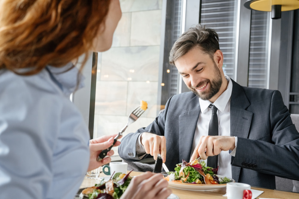 Two colleagues enjoying a salad together at work on their lunch break