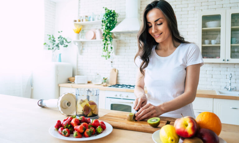 A happy woman preparing fresh fruit in her kitchen