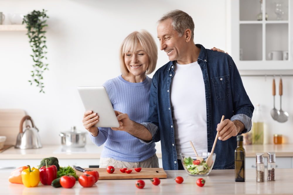 A happy couple preparing a healthy meal together in the kitchen from their personalised diet plan